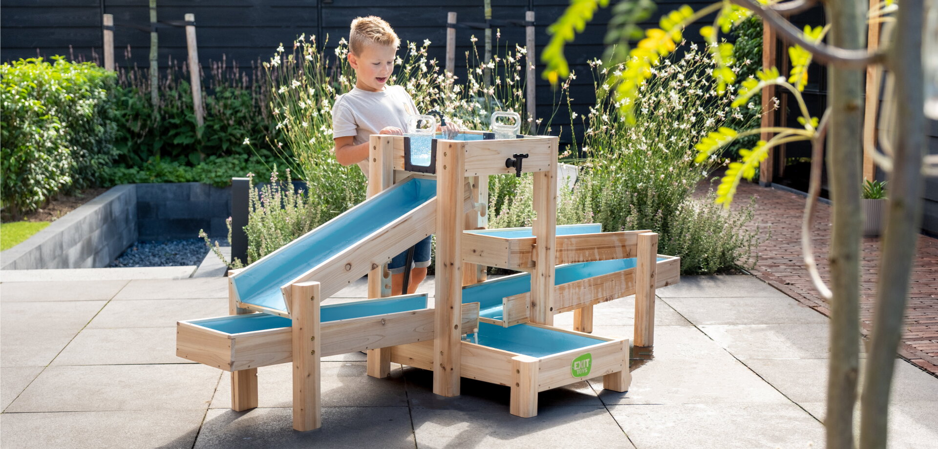 Aquaflow Wasserbahn von EXIT Toys, nachhaltiges Outdoor-Spielzeug, bei dem Kinder stundenlang Wasserspa&szlig; mit Pumpe, Schleuse und frischen Spielm&ouml;glichkeiten erleben.